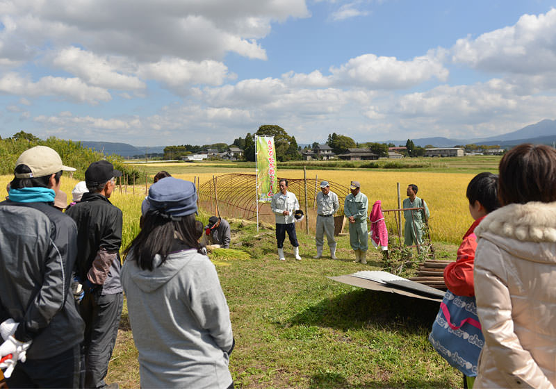 稲刈り前。交流会に参加した方たちを前にASO北外輪ファームの概要を説明する鎌倉さんらメンバーたち。