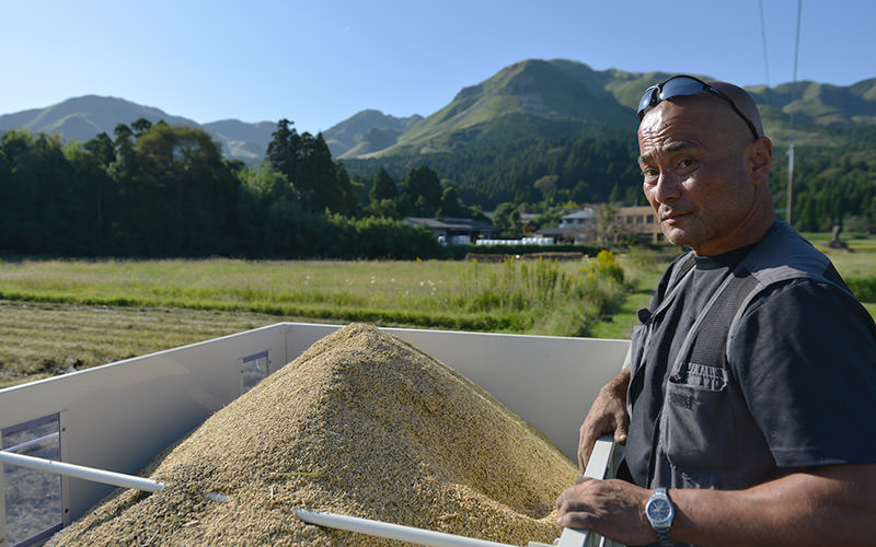 収穫したササニシキの籾と坂梨寿良さん。